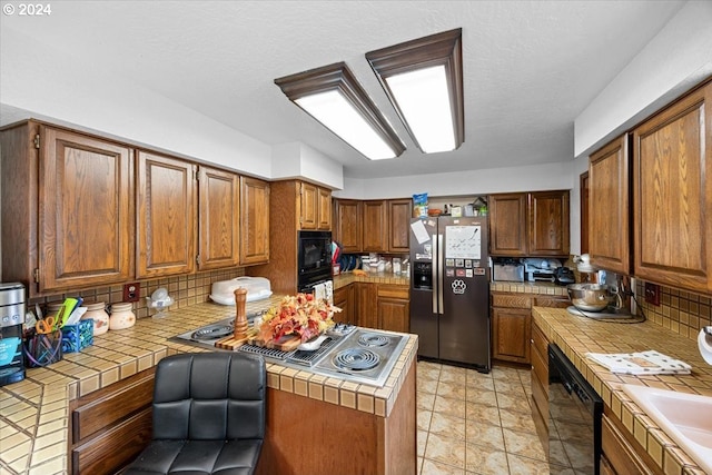 kitchen with tile countertops, tasteful backsplash, and black appliances