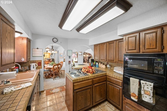 kitchen featuring kitchen peninsula, black appliances, sink, tile countertops, and light tile patterned flooring