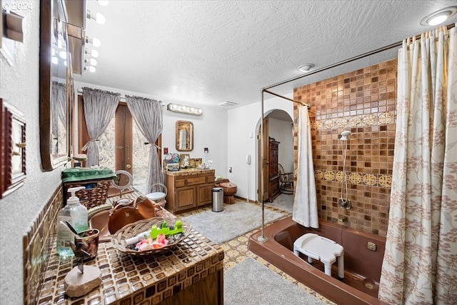 bathroom featuring shower / bath combo with shower curtain, vanity, and a textured ceiling