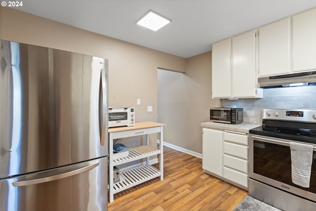 kitchen featuring white cabinets, appliances with stainless steel finishes, tasteful backsplash, and light hardwood / wood-style floors