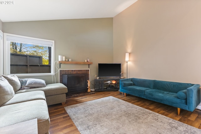 living room with a fireplace, vaulted ceiling, and dark wood-type flooring