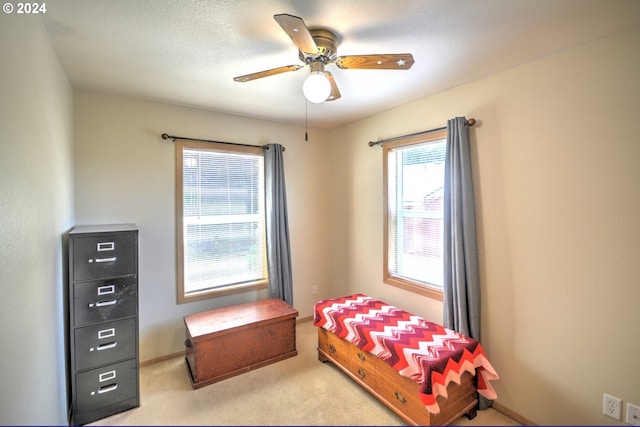 carpeted bedroom featuring ceiling fan and a textured ceiling