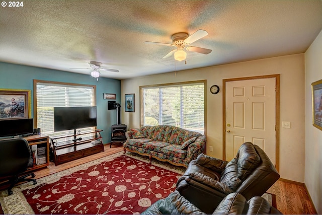 living room featuring light wood-type flooring, ceiling fan, and a wood stove