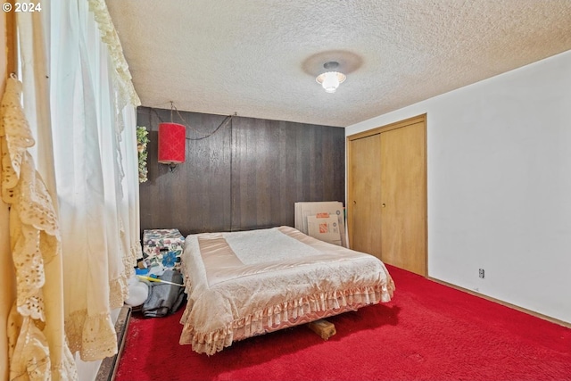 carpeted bedroom with a textured ceiling, a closet, and wood walls