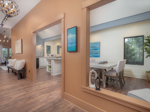 dining room with sink, a notable chandelier, vaulted ceiling, and hardwood / wood-style flooring