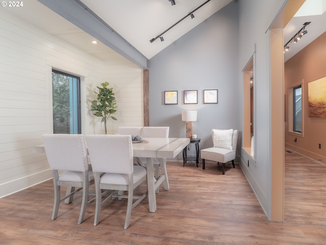 dining space with rail lighting, light hardwood / wood-style floors, and high vaulted ceiling