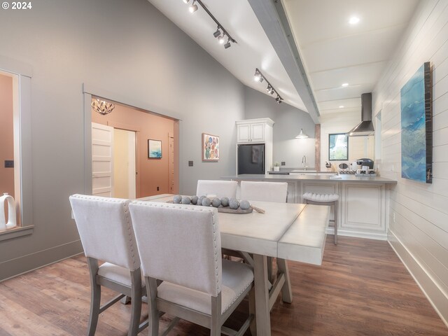 dining area with dark hardwood / wood-style floors, high vaulted ceiling, rail lighting, and sink