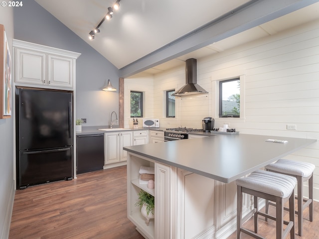 kitchen featuring rail lighting, kitchen peninsula, black appliances, wall chimney exhaust hood, and white cabinets