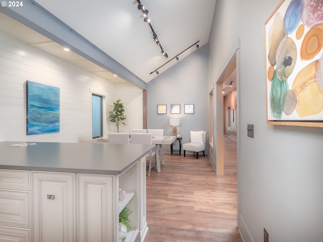 interior space with high vaulted ceiling, white cabinetry, light hardwood / wood-style flooring, and rail lighting