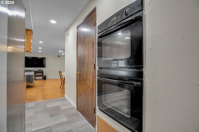 kitchen with double oven and light wood-type flooring