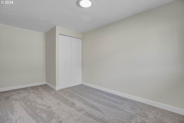 unfurnished bedroom featuring light carpet and a closet