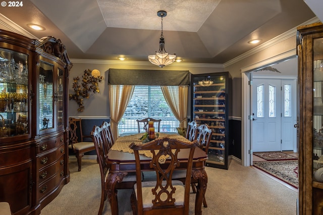 carpeted dining room with ornamental molding and a tray ceiling