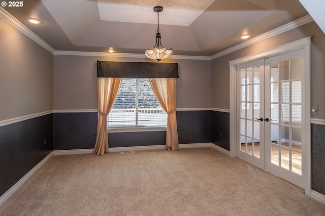 empty room with french doors, a raised ceiling, carpet, and crown molding