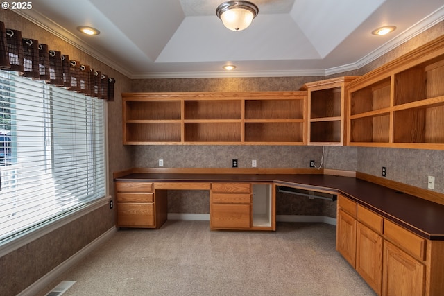 unfurnished office with visible vents, light carpet, built in desk, crown molding, and a raised ceiling