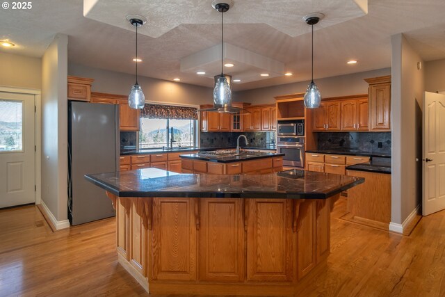 kitchen with a center island with sink, island exhaust hood, stainless steel appliances, and light wood-type flooring