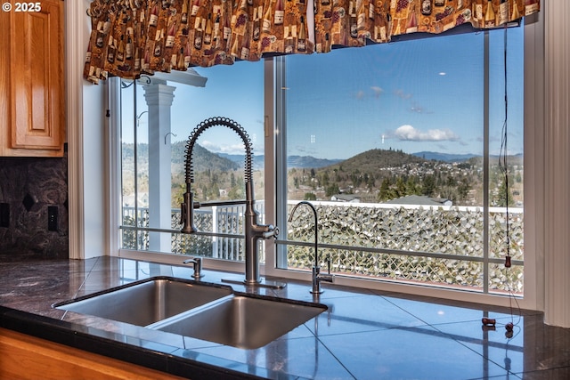 kitchen featuring a sink, dark countertops, backsplash, a mountain view, and decorative columns