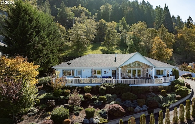 back of property with stone siding and a view of trees