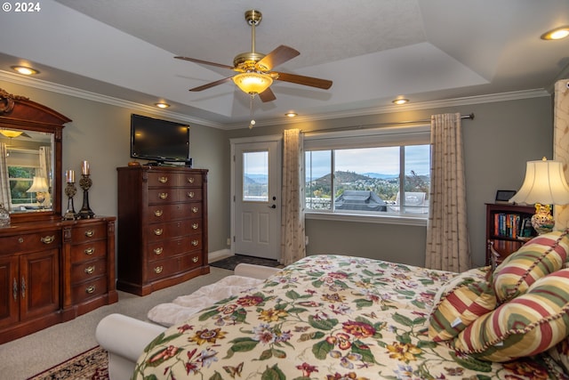 carpeted bedroom with crown molding, a tray ceiling, and ceiling fan