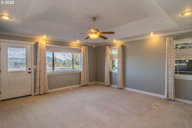 carpeted empty room featuring baseboards, a raised ceiling, ornamental molding, and a ceiling fan