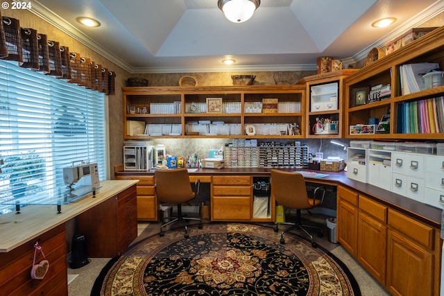 carpeted home office with built in desk, ornamental molding, and a raised ceiling