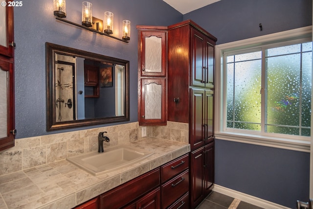 bathroom with a wealth of natural light, baseboards, vanity, and tile patterned floors