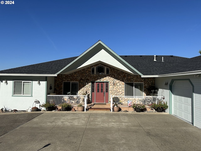 ranch-style home featuring a garage, a porch, and a shingled roof