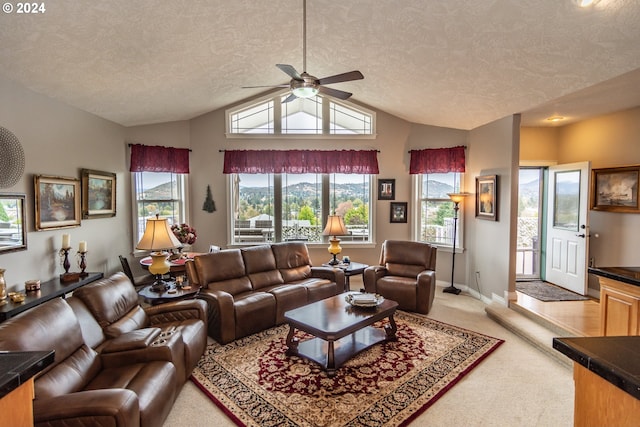 living room with lofted ceiling, a textured ceiling, baseboards, light colored carpet, and ceiling fan