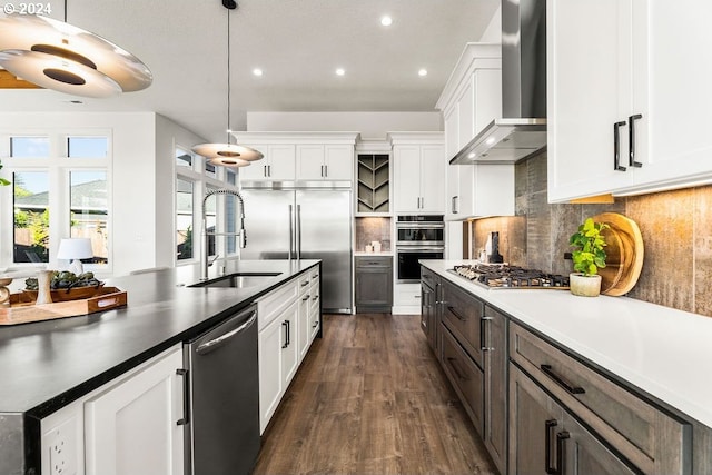 kitchen featuring wall chimney range hood, tasteful backsplash, dark wood-type flooring, appliances with stainless steel finishes, and white cabinetry