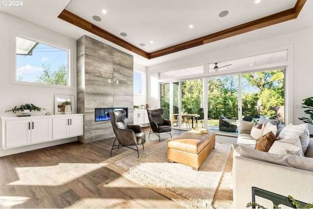 living room featuring ornamental molding, ceiling fan, a tray ceiling, and light hardwood / wood-style flooring