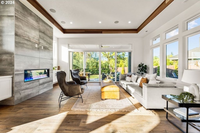 living room featuring a tile fireplace, hardwood / wood-style flooring, and a tray ceiling