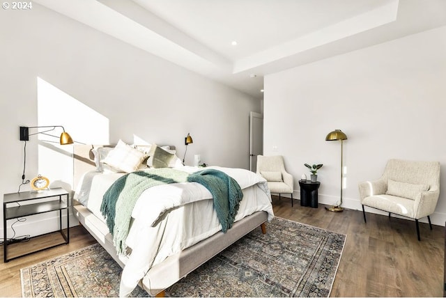 bedroom with a tray ceiling and dark wood-type flooring