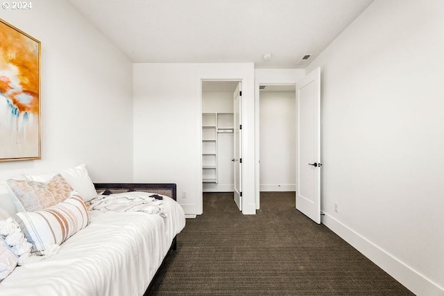 bedroom featuring dark carpet and a spacious closet