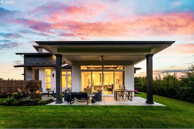 back house at dusk with a patio and a yard