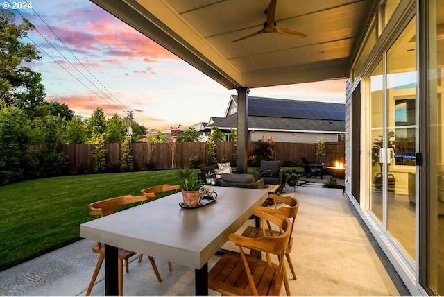 patio terrace at dusk with ceiling fan and a yard