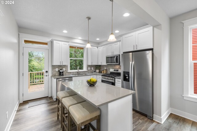 kitchen with white cabinets, a kitchen island, sink, and appliances with stainless steel finishes