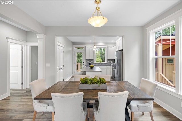 dining room with ornate columns, sink, and wood-type flooring