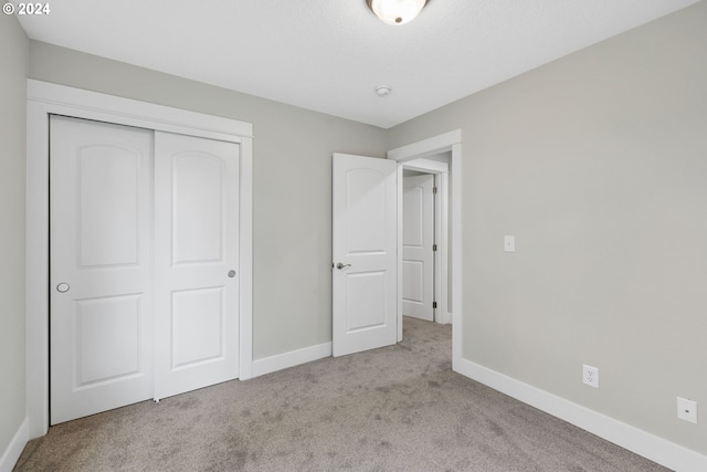 unfurnished bedroom with a closet and light colored carpet