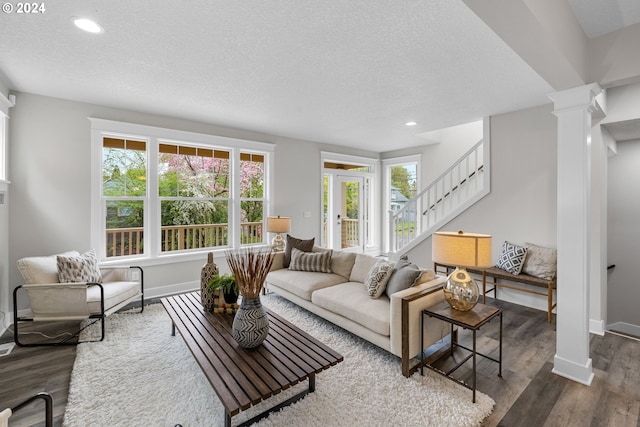 living room featuring a textured ceiling, dark hardwood / wood-style flooring, and ornate columns