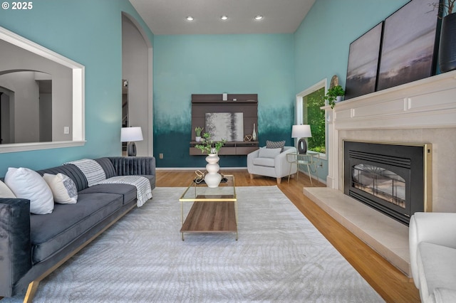 living room featuring a towering ceiling, recessed lighting, wood finished floors, and a fireplace
