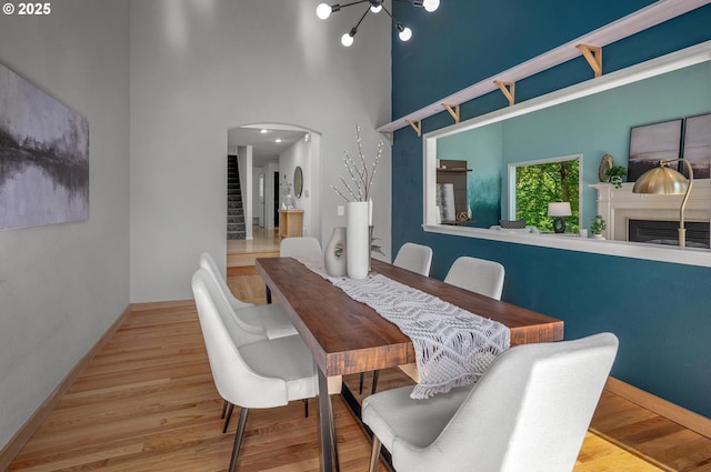 dining space with baseboards, arched walkways, wood finished floors, and a fireplace