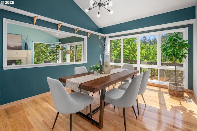 dining room with baseboards, a notable chandelier, wood finished floors, and lofted ceiling