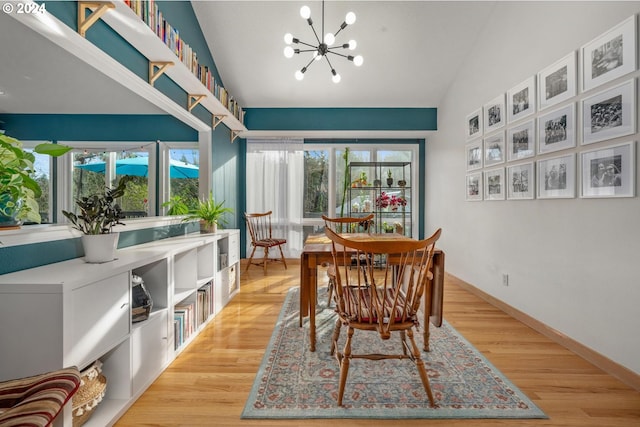 dining area with a notable chandelier, light wood-type flooring, and vaulted ceiling