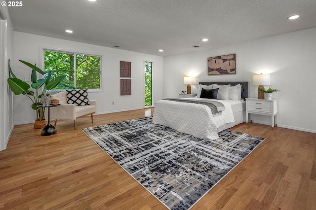 bedroom featuring a textured ceiling, baseboards, recessed lighting, and wood finished floors