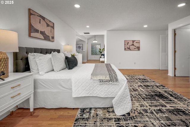 bedroom with recessed lighting, baseboards, light wood-type flooring, and visible vents