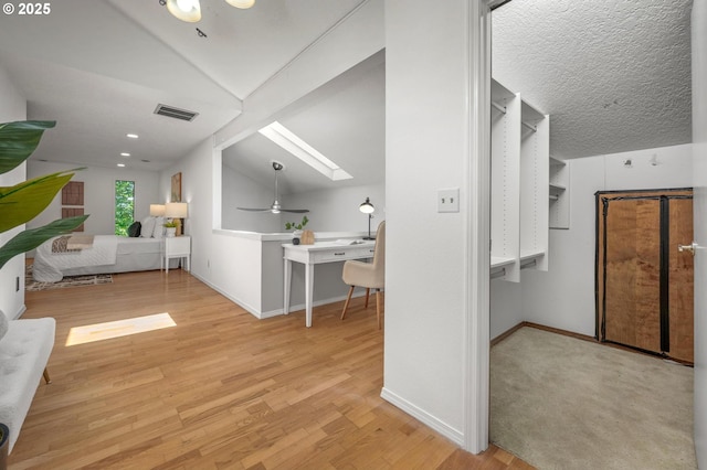 bonus room featuring vaulted ceiling with skylight, a ceiling fan, visible vents, baseboards, and light wood-style floors