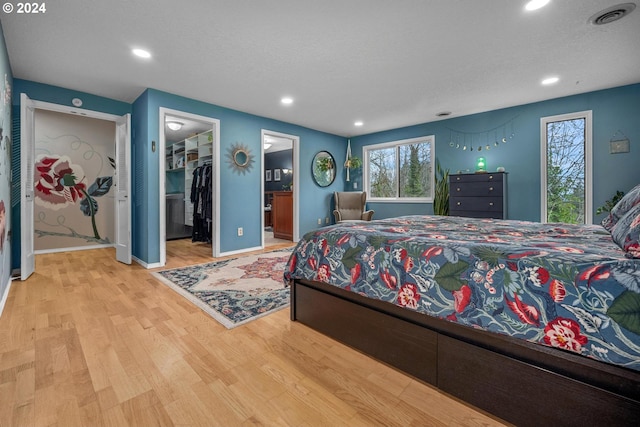 bedroom featuring light hardwood / wood-style floors, a walk in closet, a textured ceiling, and a closet