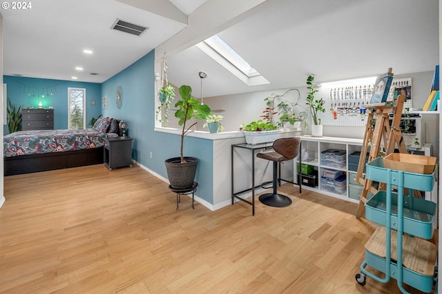 bedroom with light wood-type flooring and lofted ceiling with skylight