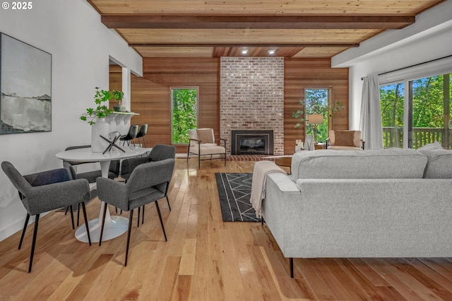 living area featuring light wood-style floors, a brick fireplace, wooden ceiling, beamed ceiling, and wooden walls