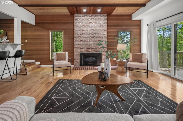 living room featuring wooden walls, wood ceiling, plenty of natural light, and a fireplace