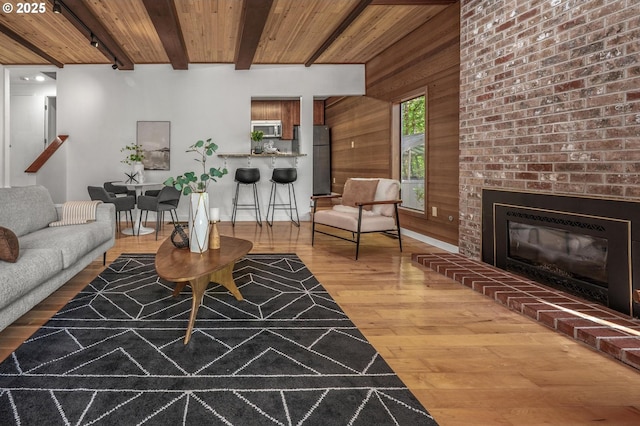 living room featuring wooden walls, wooden ceiling, beam ceiling, and wood finished floors